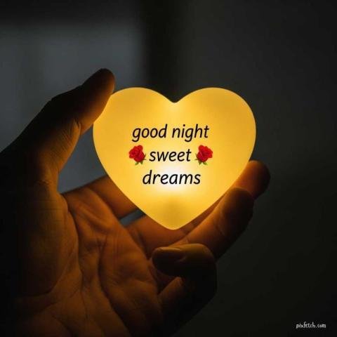 A close up of a hand gently holding a small glowing heart shaped light with good night wishes